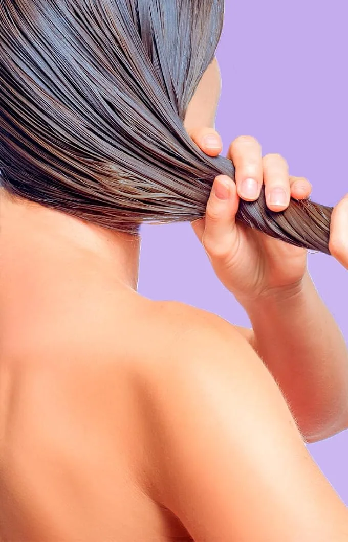A woman seen from behind gathering wet dark hair in her hand