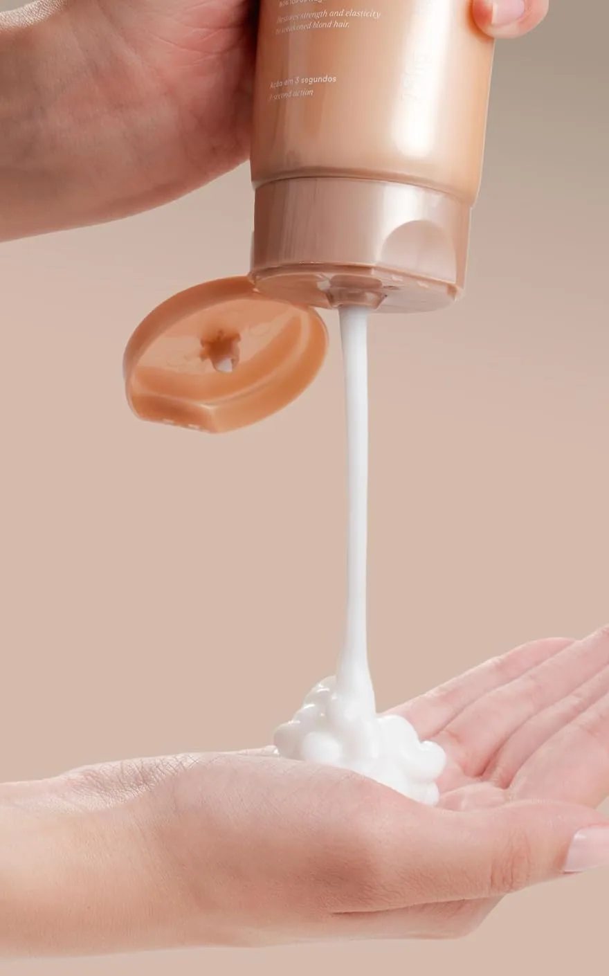 A bronze Perfect Blonde tube squeezing white cream into an open palm