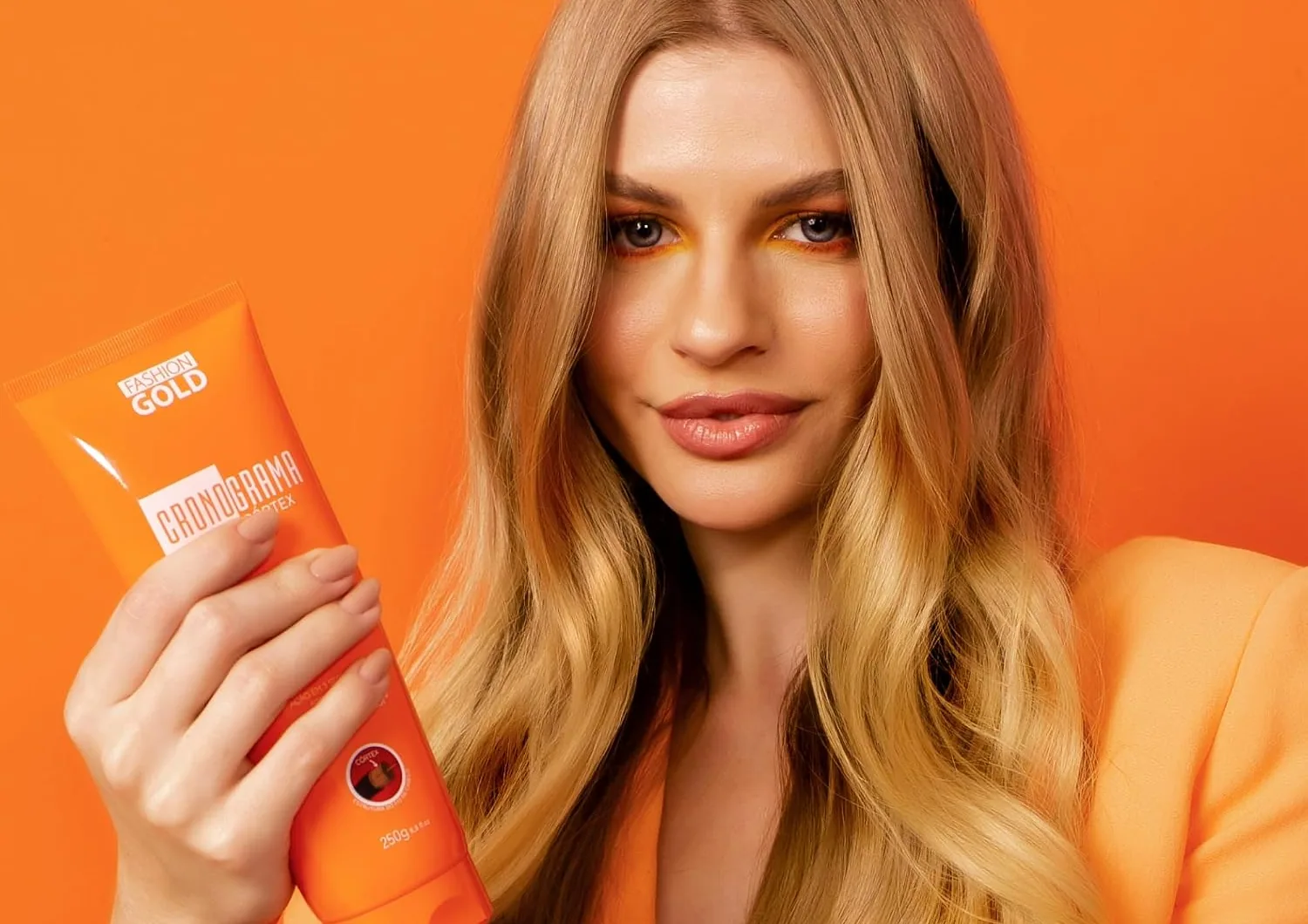 A blonde model holding the orange Cronograma Cortex tube