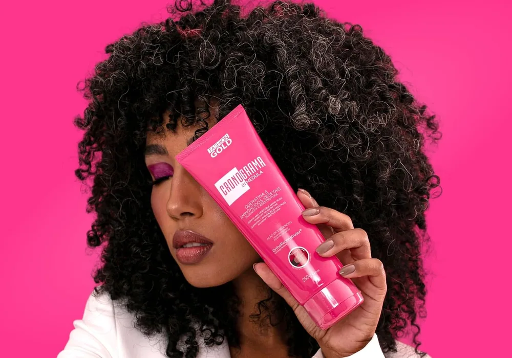 A model with dark curls holding the pink Cronograma Medula tube